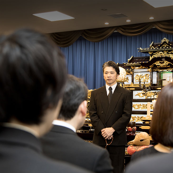 祭壇の前に立って挨拶をする喪主